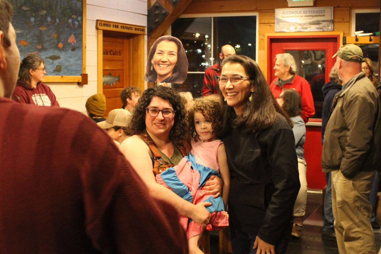 a woman poses for a picture with another woman and her daughter in a crowded indoor space of a restaurant